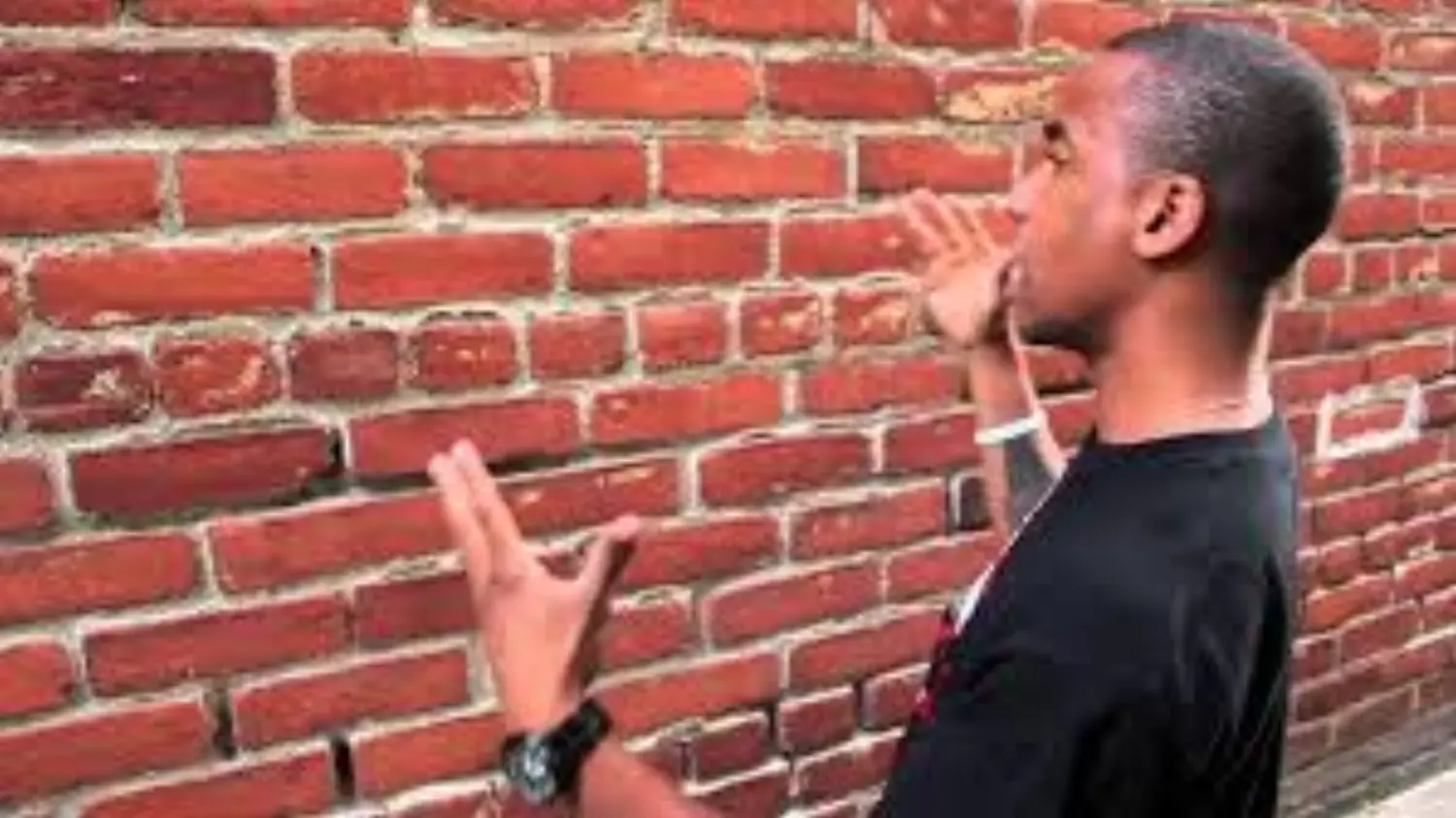 person speaking to a brick wall